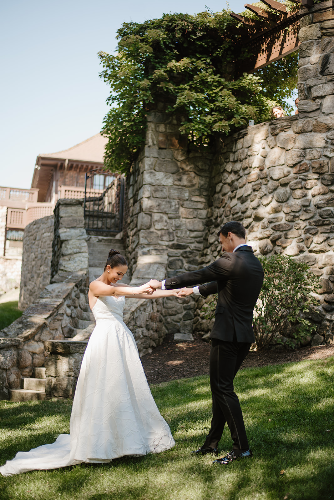 Newlyweds holding hands and smiling joyfully during their first look on the lawn of Le Chateau.